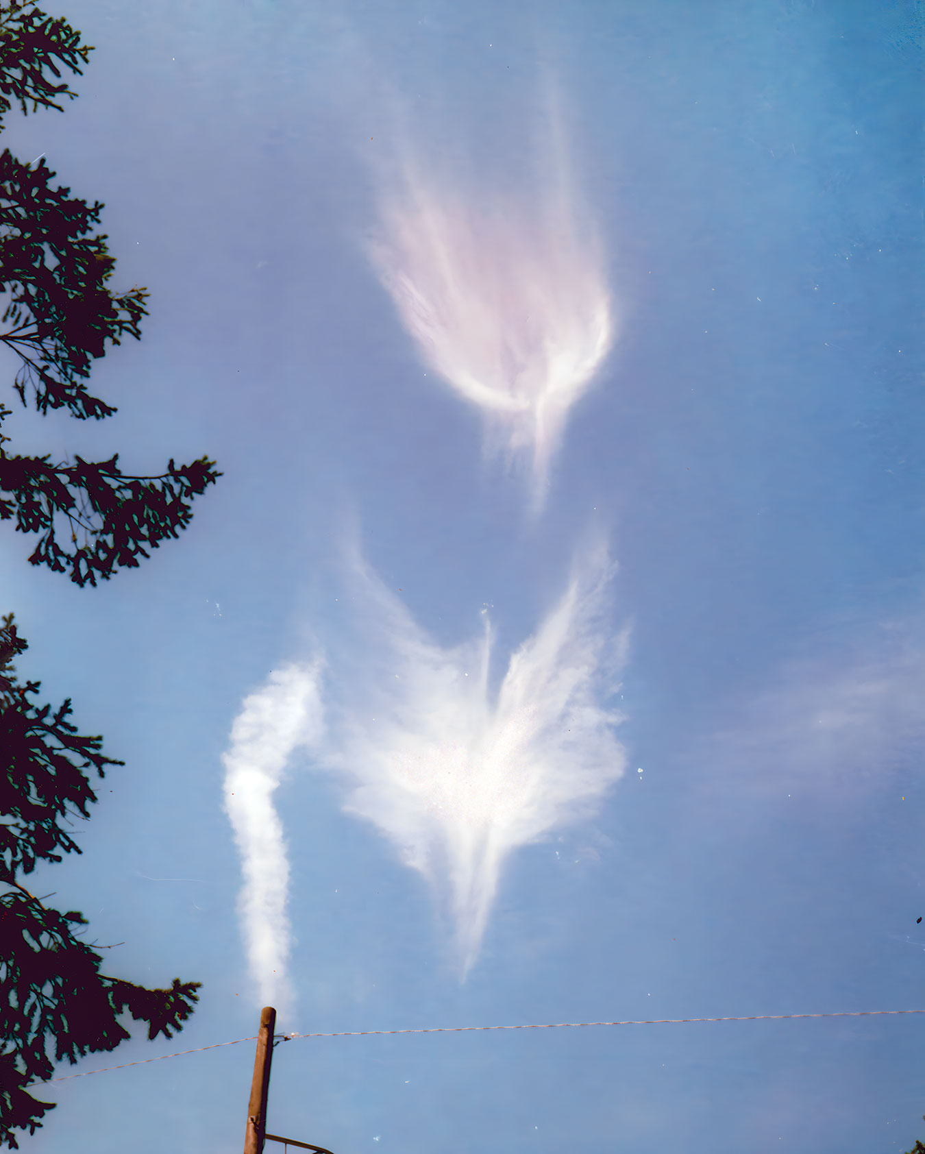 Two cloud formations shaped like angels in a bright blue sky above Amboy, Illinois — the lower figure bearing wide wings; photographed by Marianne Ball on August 16, 1998